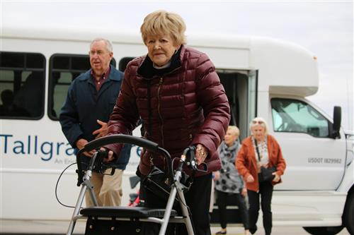 Image of senior citizen using walker to get of a community bus